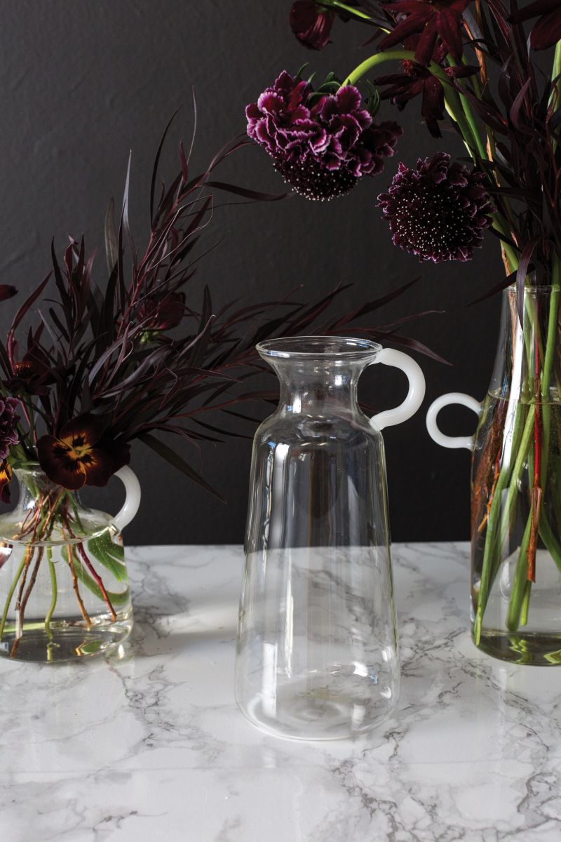 Clear pitcher shaped bud vase with solid white glass handles.