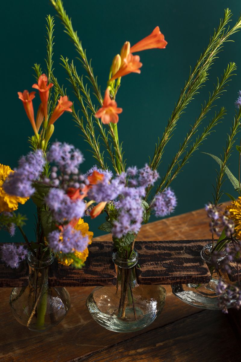 Set of four glass budvases hanging from a mango wood platform..