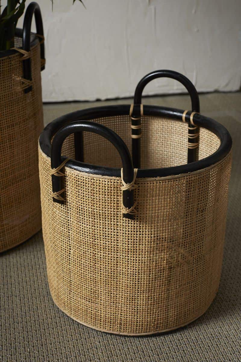 set of three woven natural baskets with black handles.