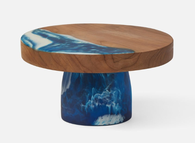 Teak and resin, two materials handcrafted together, bring a splash of color to any setting. These two-tone cake stands he are hand-dipped, making each one-of-a kind.