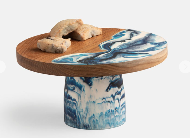 Teak and resin, two materials handcrafted together, bring a splash of color to any setting. These two-tone cake stands he are hand-dipped, making each one-of-a kind.