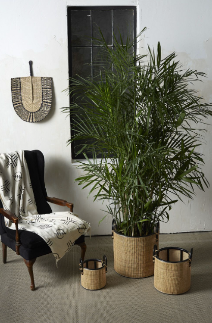 set of three woven natural baskets with black handles.