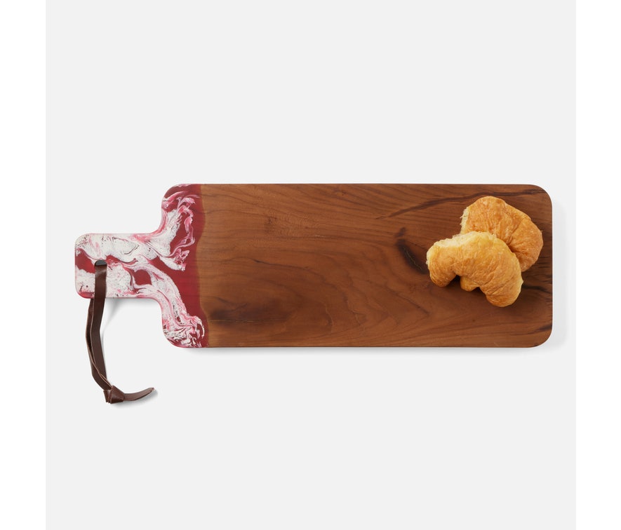 Teak board and resin handle are combined to create a one of a kind serving board. The handle is two-toned and hand-dipped in a berry color. Finished with a leather strap.